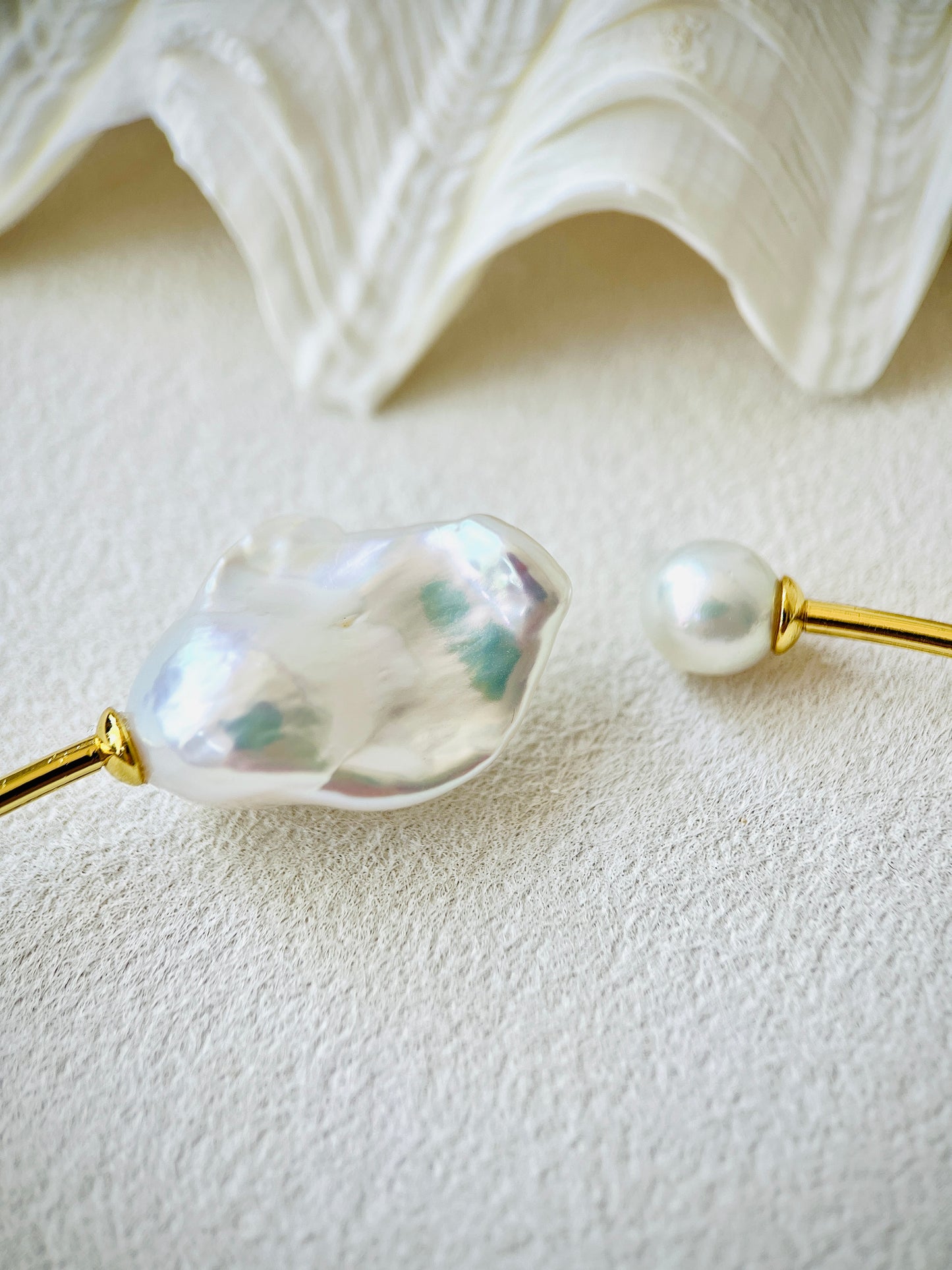 Pearl hairpin with gold accents on a textured white surface