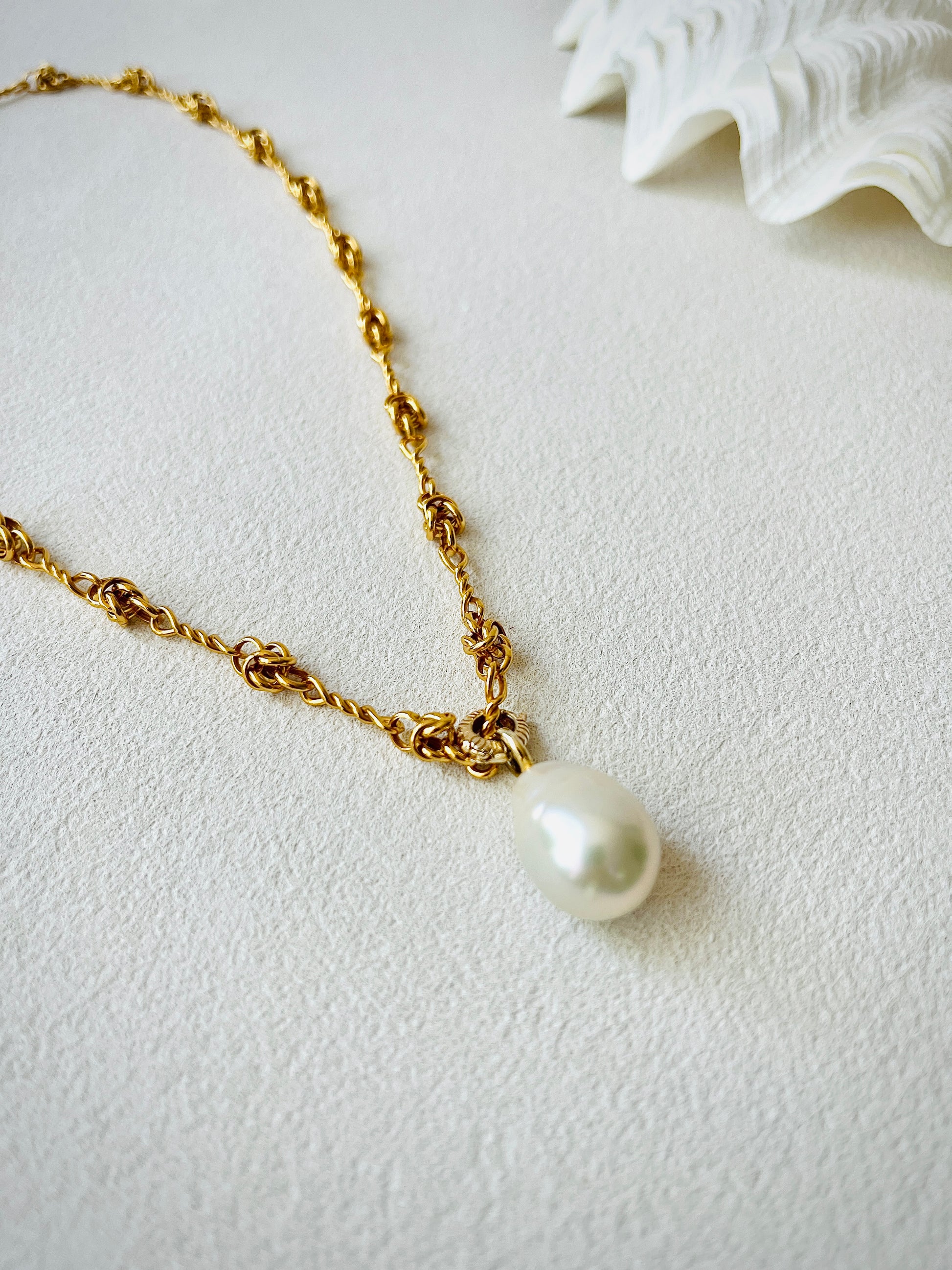 Gold chain necklace featuring a white baroque pearl pendant with high luster