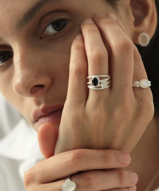 Close-up of a person wearing two rings with a neutral background