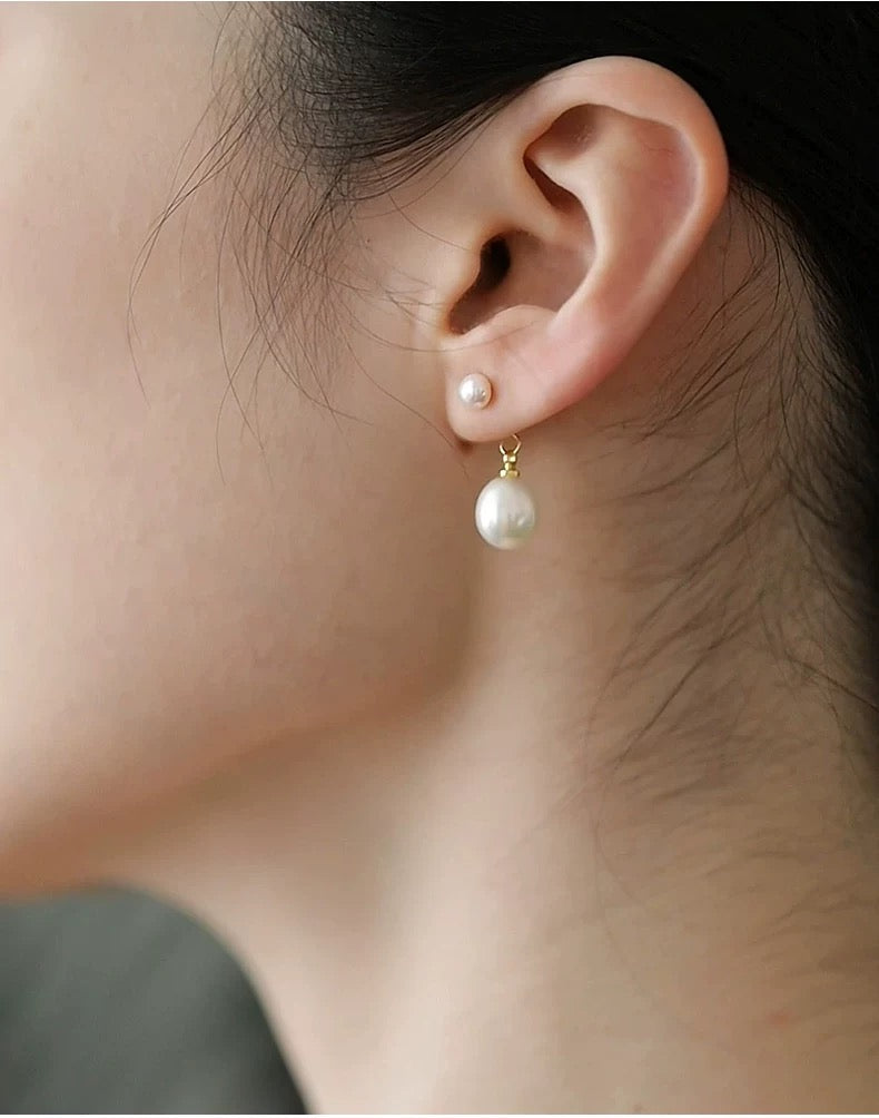 Pearl earrings being worn on an ear with a blurred background