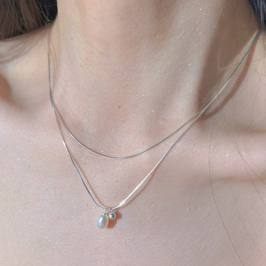 Close-up of a silver necklace with a pendant on a person's neck