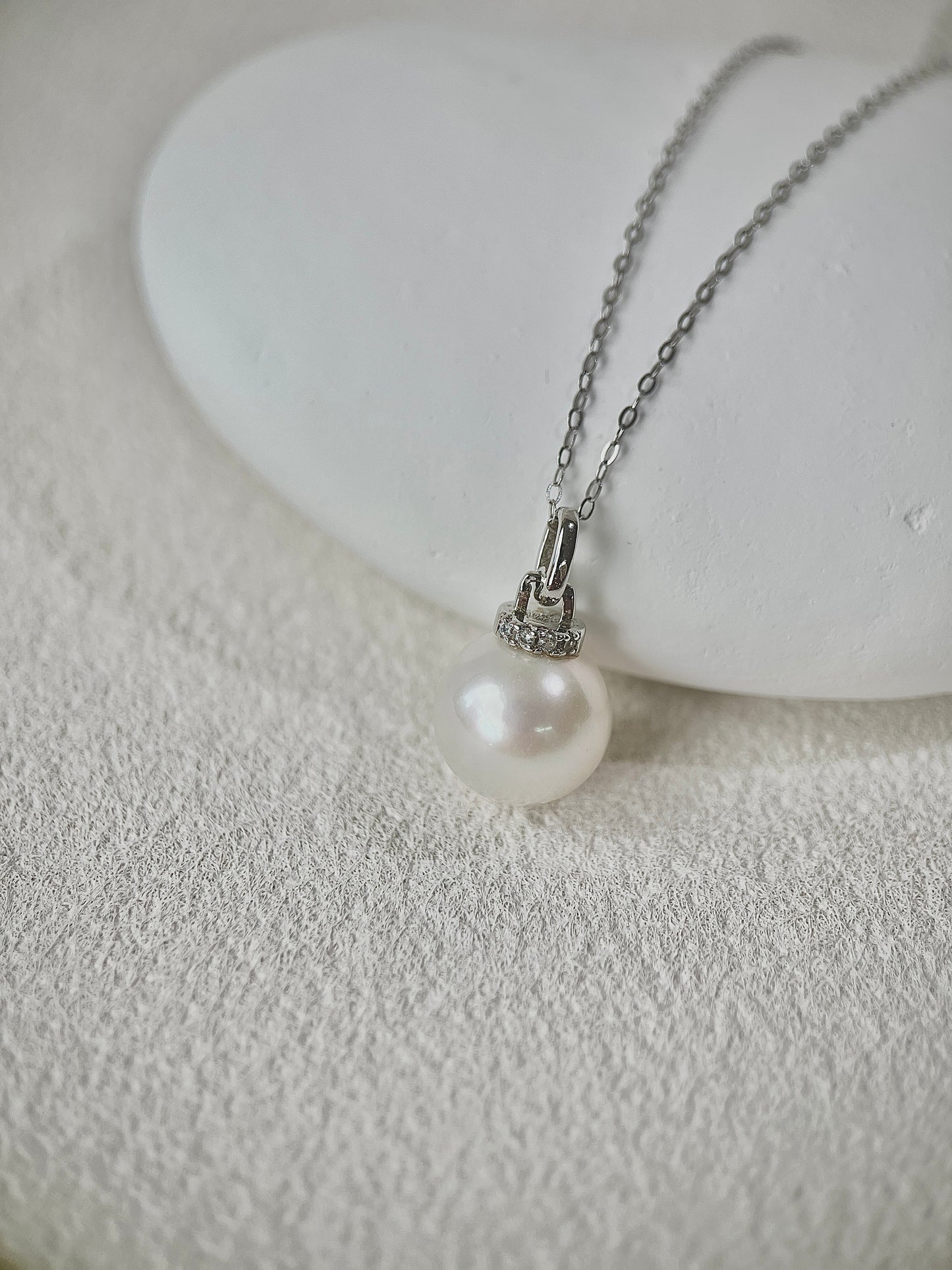Pearl Pendant necklace with silver chain on a textured white surface