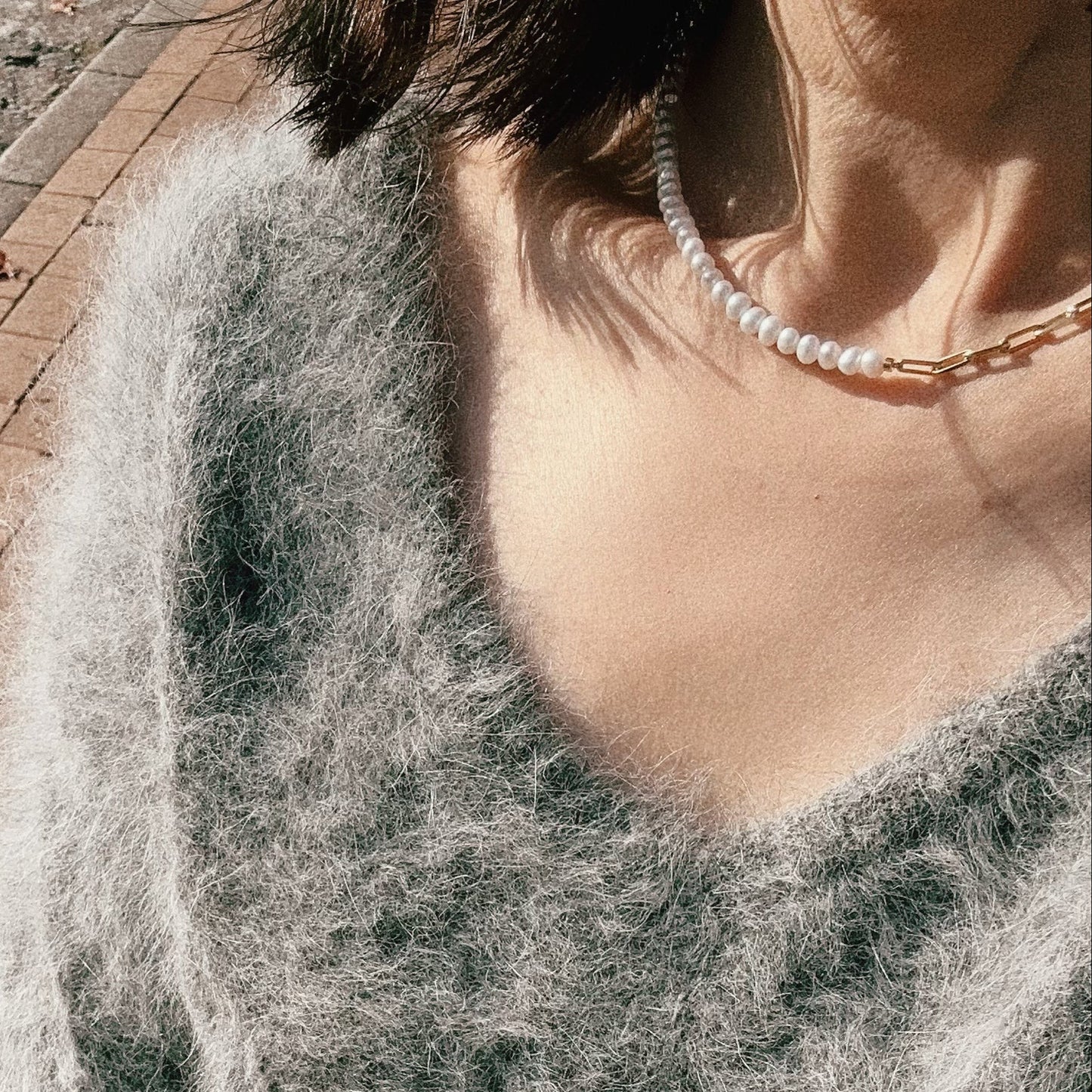 Close-up of a person wearing a pearl necklace with a blurred background