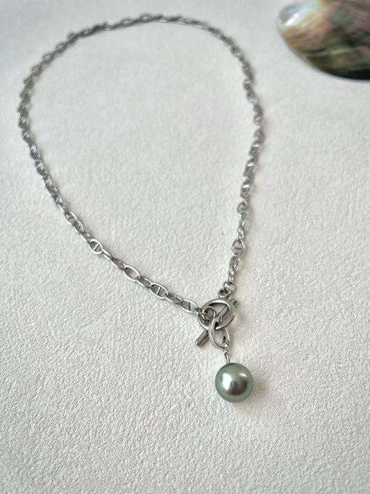 Necklace with a single pearl pendant on a light gray background