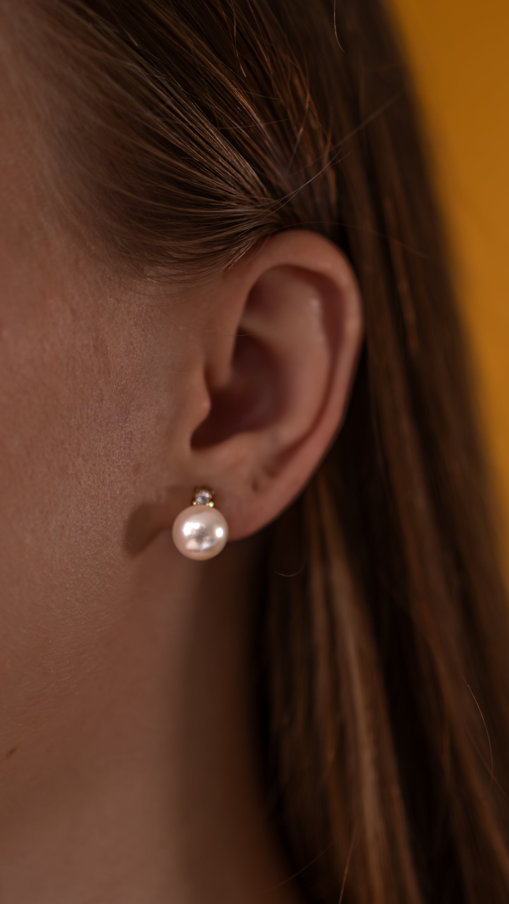 Pearl earrings worn by a female model with a blurred background
