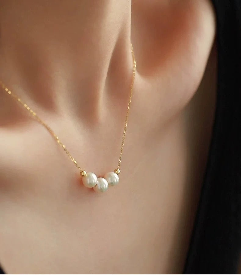 Gold necklace with pearls worn by a person