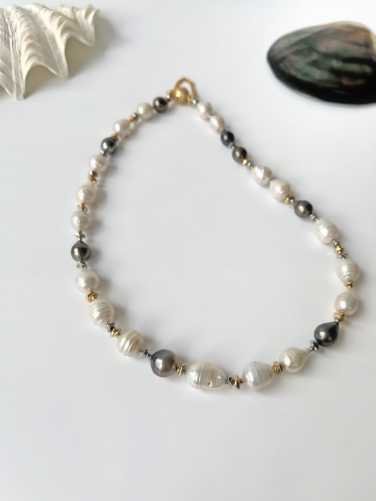 Pearl necklace with black, white and gold beads on a white background