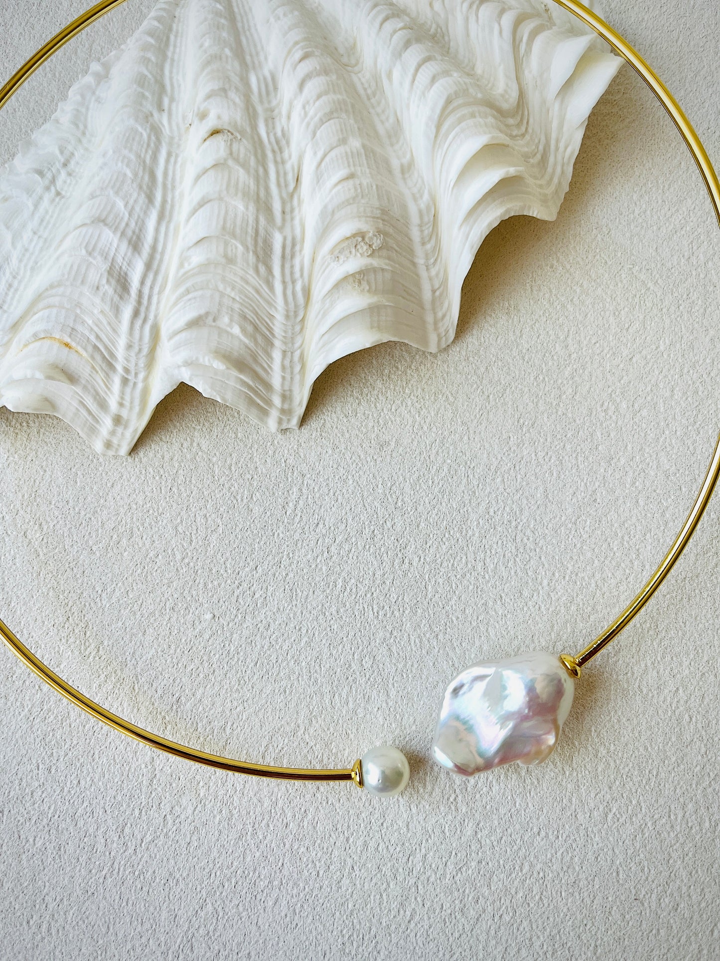 Gold necklace with pearls on a textured white surface