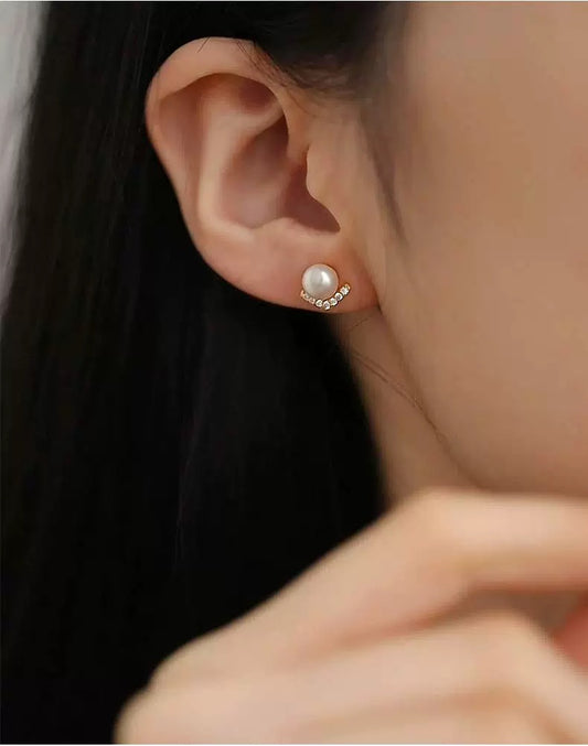 Close-up of an ear wearing a pearl earring with a blurred background