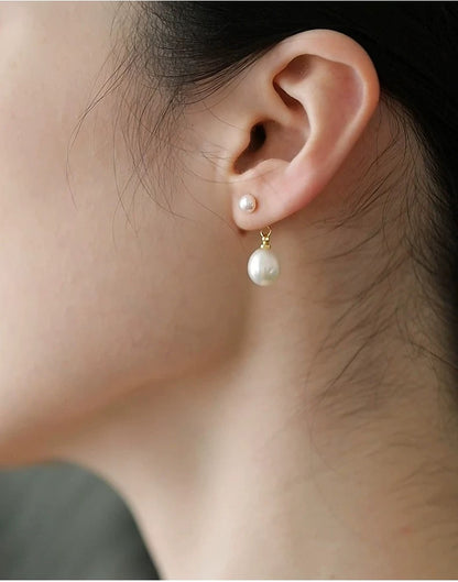 Pearl earrings being worn on an ear with a blurred background