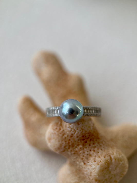 Silver ring with an Akoya pearl on a textured beige surface