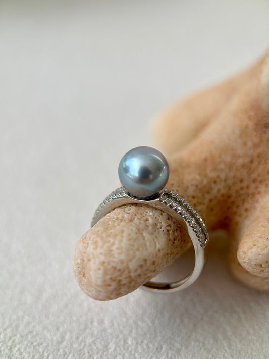 Silver ring with an Akoya pearl on a textured beige surface
