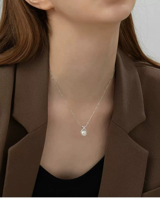 Necklace with a pendant worn by a person in a brown blazer.