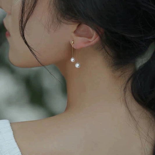 Close-up of a person wearing pearl earrings with a blurred background