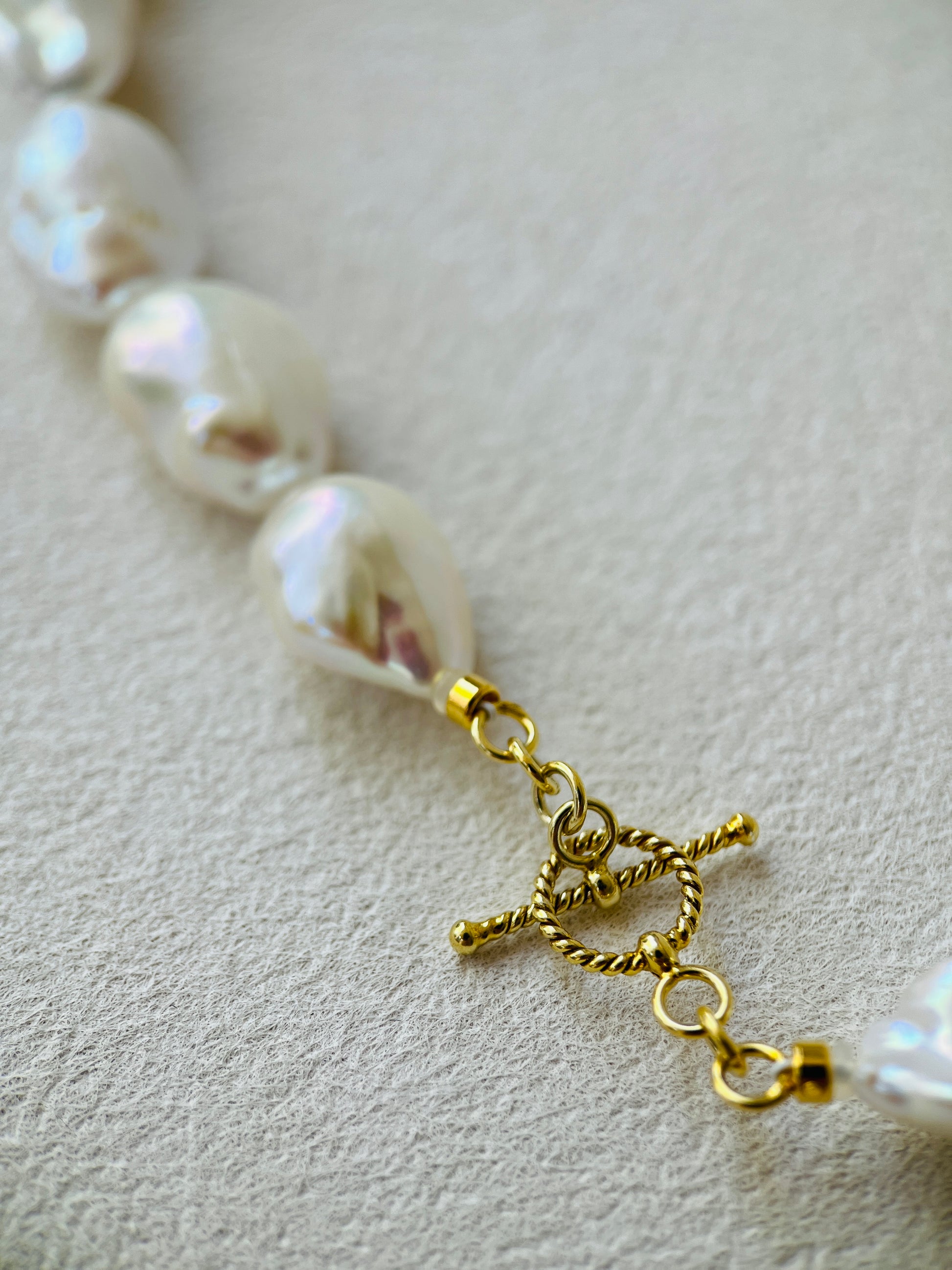 Pearl necklace with a gold clasp on a light background