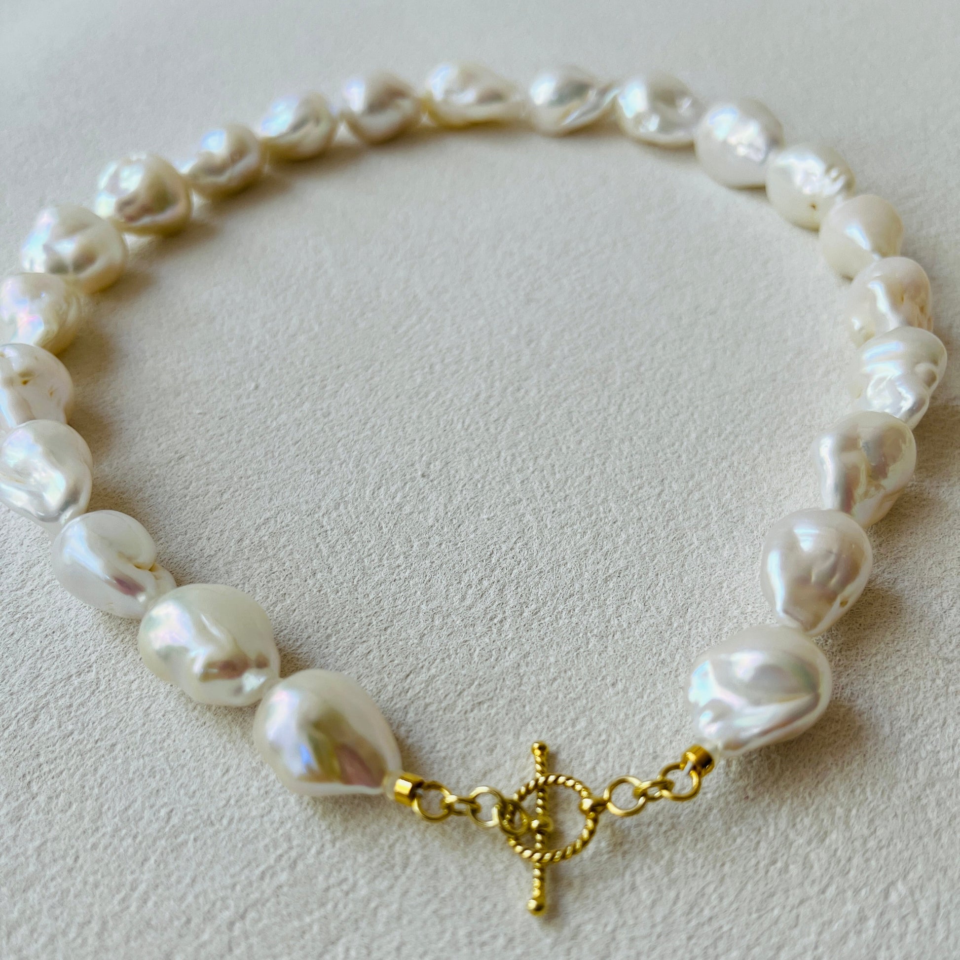 Baroque Pearl with a gold clasp on a light gray background