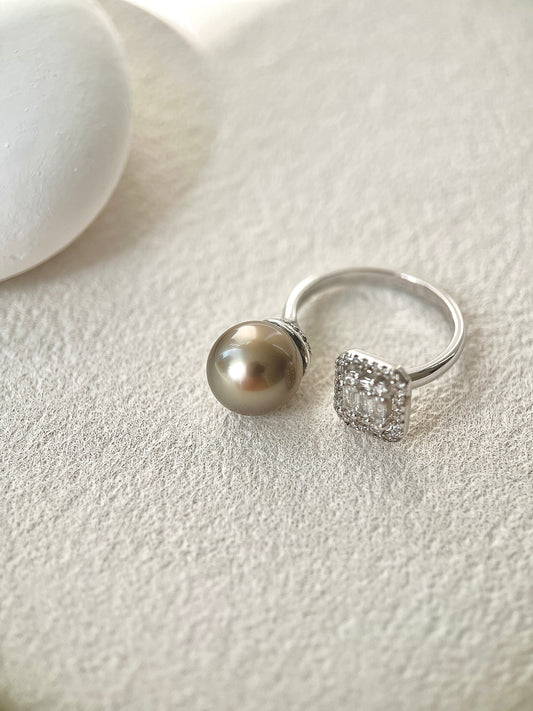 Silver ring with a tahitian black pearl and another ring with a diamond on a light gray surface