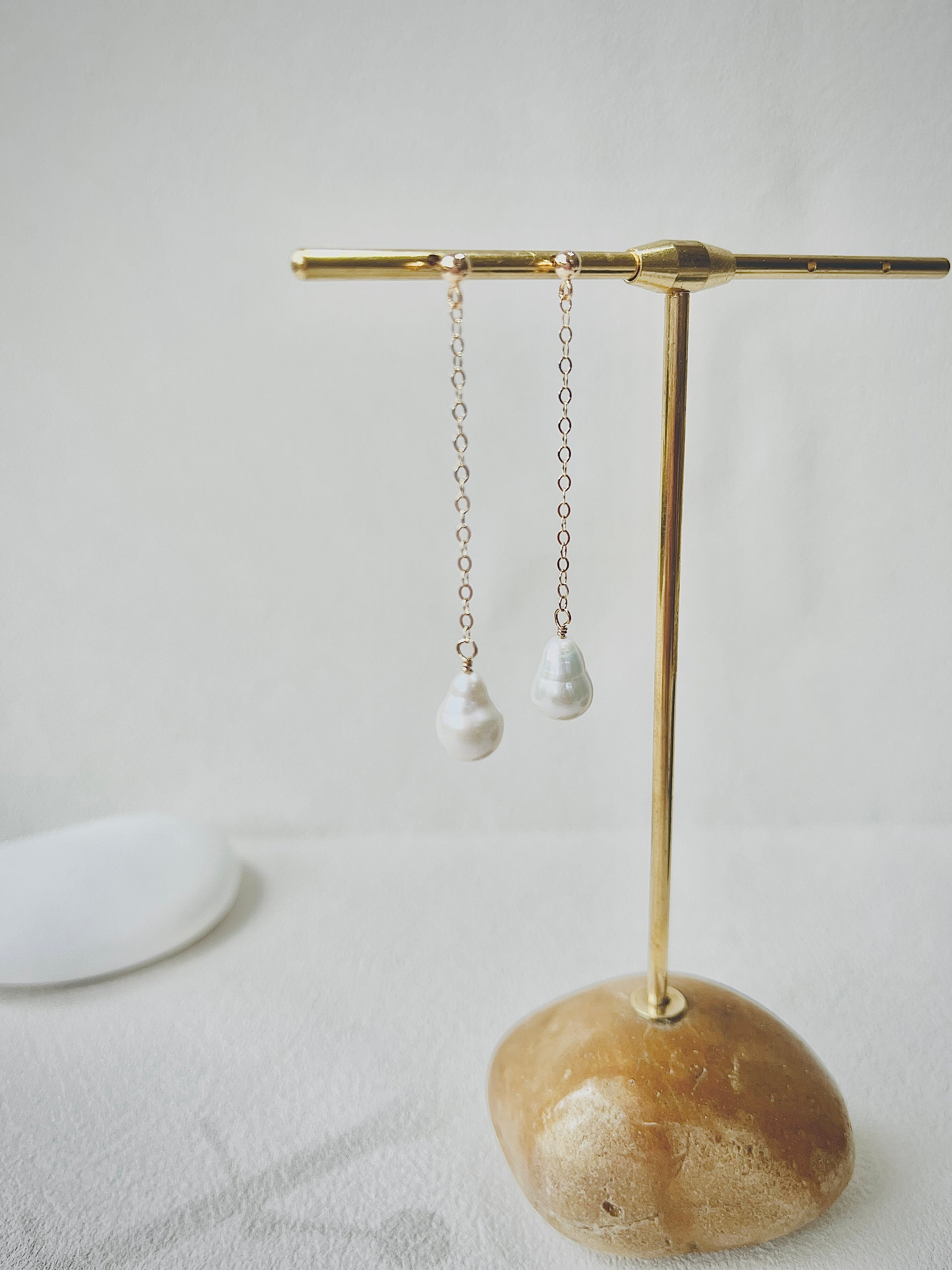 Pearl earrings on a gold earring stand with a neutral background