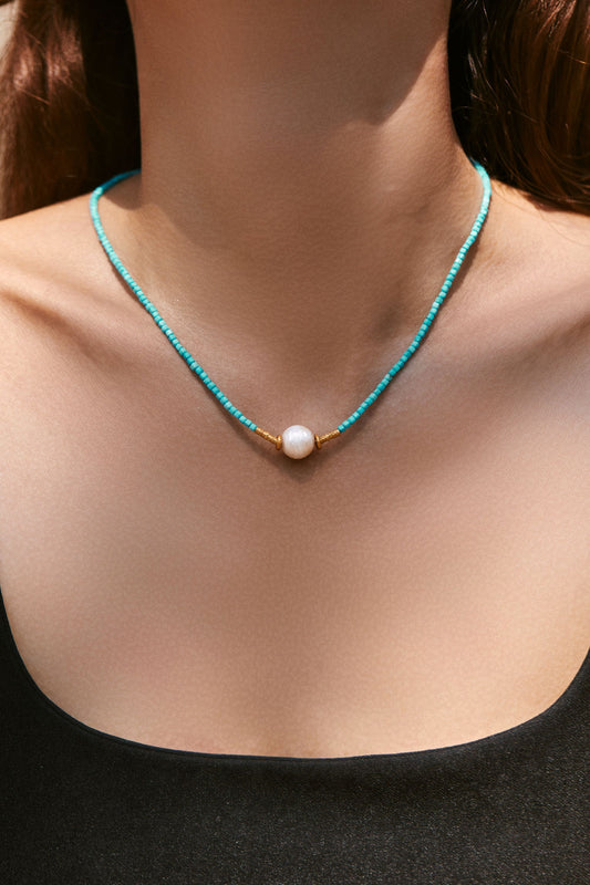Turquoise beaded necklace with a pearl pendant on a women
